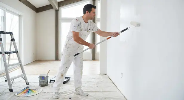 Professional painter using a roller to apply fresh paint to a living room wall